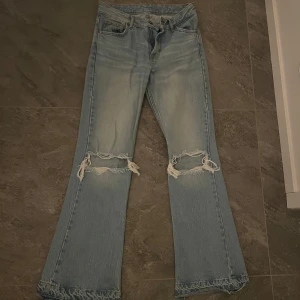 Ljusa jeans med slitningar från Pull&Bear - Snygga ljusblå jeans från Pull&Bear med slitna detaljer på knäna. De har en klassisk femficksdesign och knappgylf. Mid waisted och super långa med bootcut. Älskar dessa men de är för små för mig tyvärr! 
