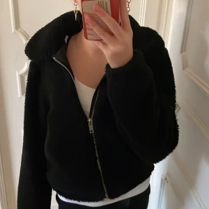 Svart teddyjacka - Mysig svart teddyjacka i damstorlek XXS. Perfekt för kyliga dagar med sitt mjuka och varma material. Jackan har en dragkedja framtill och långa ärmar. Den är i mycket bra skick och passar perfekt för höst och vinter.