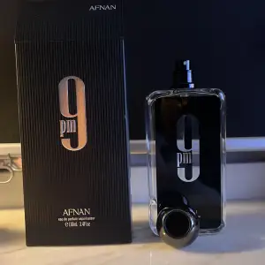 Säljer en flaska 9pm Eau de Parfum från Afnan. Den har en stilren svart design med silverdetaljer och en rund kork. Doften är en mix av vanilj, amber och varma kryddor med inslag av kanel och fruktiga toner. Perfekt för kvällar när du vill sticka ut! 🌟