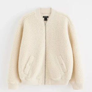 Beige teddyjacka från Lindex  - Mysig beige teddyjacka från Lindex  i storlek S. Perfekt för kyliga dagar med sin fluffiga och varma design. Jackan har dragkedja och ribbade muddar vid ärmslut och nederkant. Den är långärmad och passar perfekt till både vardag och avslappnade tillfällen.