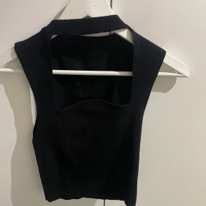 Svart ärmlös topp med öppen rygg - Snygg svart ärmlös topp med en stilren design och öppen rygg. Perfekt för en trendig look.