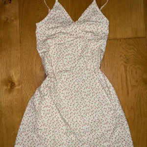Blommig sommarklänning - Söt blommig klänning med smala axelband och v-ringning. Perfekt för sommardagar och midsommarfirande. Klänningen är i mycket bra skick och gjord av ett lätt och bekvämt material.