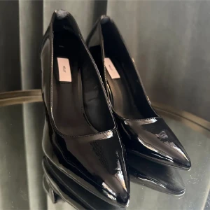 Svarta lackpumps med spetsig tå - Snygga svarta lackpumps i nytt skick med spetsig tå och hög klack. Perfekta för festliga tillfällen eller en utekväll. De har en elegant och klassisk design som passar till många olika outfits. (Lånade bilder) klack 10cm