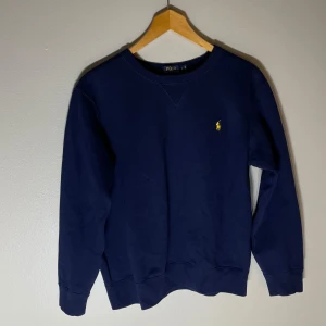 Mörkblå Ralph lauren sweatshirt - Hej, säljer en mörkblå Polo Ralph Lauren tröja i storlek L. Tröjan har en gul klassisk broderad logga på bröstet. Skick 8/10. Skriv vid mista fundering.MVH Jack von grisch