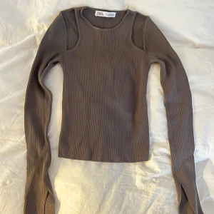 Ribbad topp från Zara - Fin topp i väldigt bra skick med snygga cut out detaljer, säljer då den är lite för liten! Färgen är brun/grå