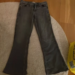Grå bootcut jeans från Gina Young  - Snygga grå bootcut jeans från Gina tricot young  med klassisk femficksdesign och dragkedja. Perfekta för en avslappnad stil med en touch av retro. Passar bra till sneakers eller boots.