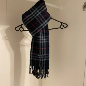 Burberry - Säljer nu denna Snygga halsduk från Burberry i blått. Tillverkad i 100% mjuk kashmir med klassiskt fransad kant. Perfekt för att hålla dig varm och stilren under kyliga dagar. Hör av er vid funderingar☺️