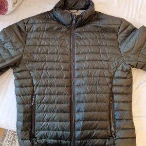 Grön quiltad jacka från Colmar - Snygg grön quiltad jacka från Colmar med dragkedja framtill och två praktiska fickor. Perfekt för kyligare dagar med sin stilrena design och bekväma passform. Inga slitningar eller missfärgningar. Perfekt skick och väl omhändertagen. 