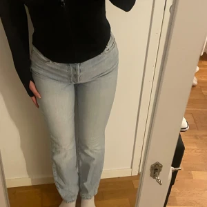 Ljusblå jeans - Säljer ett par ljusblå straight jeans med medelhög midjehöjd. De har en design med fem fickor och knappgylf. Använd ett par gånger. 