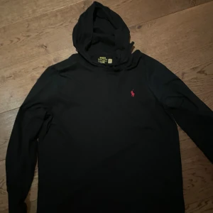Svart tröja Polo Ralph Lauren - Säljer en tröja med liten luva och snören. Använd fåtal gånger och är i nyskick. Den är väldigt tunn och bra till sommarn.