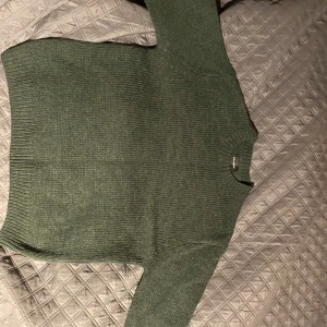 Stickad tröja - Säljer en snygg grön stickad tröja från Pull&Bear. Perfekt för kyliga dagar med sin mjuka och bekväma passform. Tröjan har långa ärmar och en klassisk rund halsringning. Använd cirka 10 gånger så fortfarande i bra skick. Nypris 500kr inköpt på asos, mitt pris är 200kr
