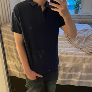 Mörkblå pikétröja från Ralph Lauren - Snygg mörkblå pikétröja från Ralph lauren skön pass form, classic fit small. Tröjan är perfekt för en skön stilren look. Köpt för 1200 säjs nu för endast 399kr🙌🙌!!Det är spegeln som är smutsig inte tröjan!!!