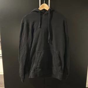 Svart hoodie från Peak Performance - Säljer en stilren svart hoodie från Peak Performance. Den har en klassisk design med en stor ficka framtill och justerbar huva. Perfekt för en avslappnad look.