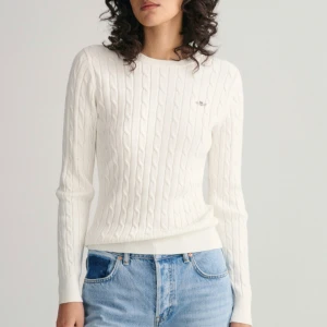 Vit kabelstickad tröja från GANT - Säljer en stilren vit kabelstickad tröja från GANT. Tröjan har en klassisk design med rund hals och långa ärmar. Perfekt för en elegant och avslappnad look.
