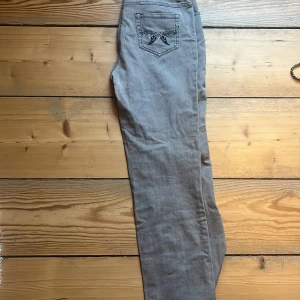 Grå jeans från Cappuccino som jag köpte från Sellpy så vet inte hur använda dom är men inget slitage som jag kan se  - Snygga grå jeans från Cappuccino med broderade detaljer på bakfickan. De har en klassisk femficksdesign och dragkedja. Perfekta för en stilren look.
