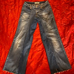 Lågmidjade bootcut jeans med coola fickor  - Snygga blå lågmidjade bootcut jeans. Fickorna och stygnen påminner lite om true religion byxor. Röda detalijer på märket stygnen. Märket är fornarinc.