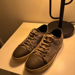 Gråa lanvins  - Snygga grå sneakers med svarta tåhättor och snörning. Perfekta för en avslappnad stil. Skorna har en robust sula och är tillverkade i ett slitstarkt material.