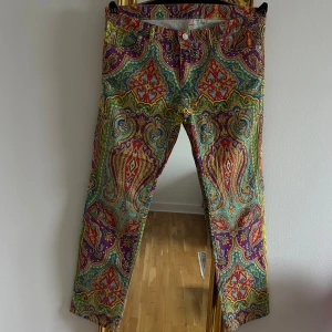 Färgglada mönstrade bogner byxor  - Unika Bogner jeans (byxor) med ett färgglatt och detaljerat mönster i rött, blått, gult och lila. Byxorna har en normal passform och är perfekta för att sticka ut med sin livfulla design. De har knappar och dragkedja framtill samt fickor både fram och bak.