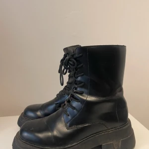 Svarta boots med snörning och dragkedja - Snygga svarta boots i skinn med både snörning och dragkedja för enkel på- och avtagning. De har en robust sula som ger bra grepp och en cool look. Perfekta för en edgy stil.