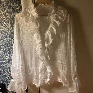 Vit elegant blus. - En vit stilfull blus, som går att både klä upp och ner. Luftig och lösare passform med resorband i handlederna.