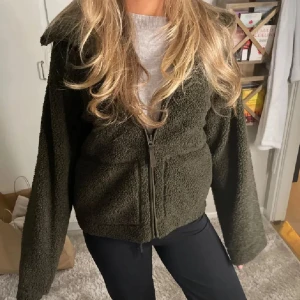 Olivgrön teddyjacka med dragkedja - Skitsnygg Teddy jacka från hm. Helt slutsåld! Den är i strl M, de är inte så stora i storleken så passa mig bäst som har S. Är 175cm och den går hela vägen ut i armarna. Säljer även i beige🤍