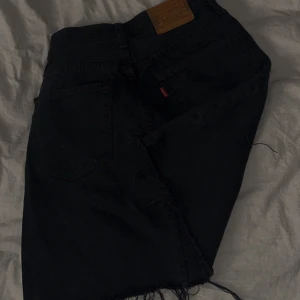 Svart jeanskjol från Levi's - Snygg svart jeanskjol från Levi's med fransig nederkant. Kommer ej till användning 