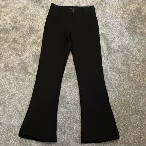 Svarta bootcut low waist/mid waist byxor - Snygga svarta bootcut byxor med låg midja och knappar fram. Byxorna har två bakfickor med knappar och är perfekta för en stilren look. Passar bra till både vardag och mer uppklädda tillfällen. Köptes från ginatricot för 499kr men säljer för 350kr eftersom att jag inte har advänt de så mycket! Är öppen för prisförslag👖kom privat för fler bilder!