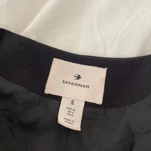 Svart kavaj från Savannah - Snygg svart kavaj från Savannah i storlek S. Den har en dubbelknäppt design med rundad hals och långa ärmar. Perfekt för en stilren look.