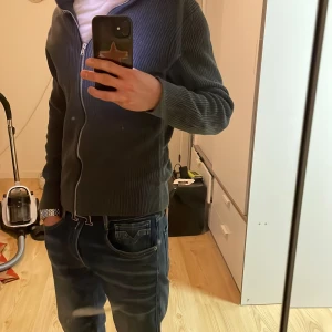 Grå stickad (Cardigan) fullzip - Säljer en stilren grå stickad fullzip från brothers. Riktigt snygg o varm och passar bra till många outfits. Inte använd mycket alls. Jag är 174 för refferens🤝 storlek S