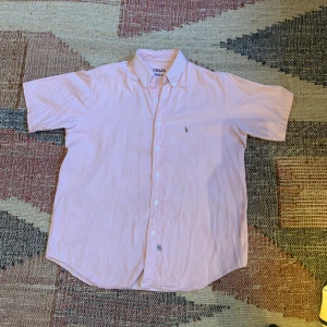 Ralph Lauren skjorta  - En fin och stilren skjorta från Ralph Lauren med ett snyggt rosa vitt randigt mönster, skjortan är i ett väldigt bra skick! Hör av dig vid eventuella frågor eller funderingar!
