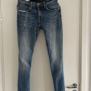Blå jeans Lee - Snygga blå jeans från Lee i modellen Rider. De har en lätt slitning vid fickorna och en dragkedja. 