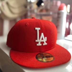 Röd keps från New Era🌺 - Snygg röd keps från New Era med broderad vit logga framtill. Modellen är 59FIFTY och har en klassisk passform. Perfekt för att ge din outfit en sportig touch. Stl 53,9 cm passar mig som är tjej med ganska litet huvud 🌺Orginal pris 600kr ❤️Andvänd ca 4 gånger i nyskick!