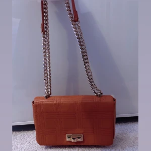 axelväska med kedja - Snygg axelväska med kedjedetaljer och ett elegant lås framtill. 