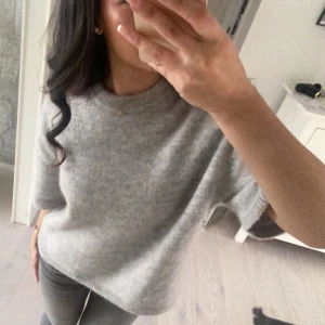 Ljusgrå stickad tröja från Gina Tricot - Mysig ljusgrå stickad tröja med korta ärmar. Perfekt för en avslappnad stil och enkel att matcha med olika outfits. Använt ett fåtal gånger🤍✨
