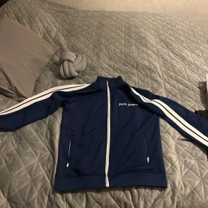 Palm angels kofta  - Dett är en stilren och trendig Palm Angels-kofta i en djup blå nyans som jag tycker är den snyggaste färgen på dessa koftor. Och något som gör denna koftan till det bättre är att man kan variera ganska mycket när man man vill ha den på sig, du kan ha den på fest, till middagskväll eller även till en vanlig enkel dag i skolan.  Och tröjan är ganska bekväm att ha på sig, så för mer bilder och funderingar tveka inte!