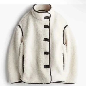 Vit teddyjacka med svarta detaljer - Säljer en mysig vit teddyjacka med svarta kantdetaljer och knäppning framtill. Jackan har en hög krage och långa ärmar, perfekt för kyliga dagar. Den är både stilren och bekväm, ett måste i garderoben!😍 säljer den pågrund av att den är förstor😿
