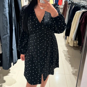 Svart prickig klänning - Säljer en svart klänning med vita prickar och v-ringad design. Klänningen helt ny 