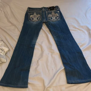 Blå jeans med broderade bakfickor - Snygga blå jeans från Miss Me,  bootcut-stil och låg midja