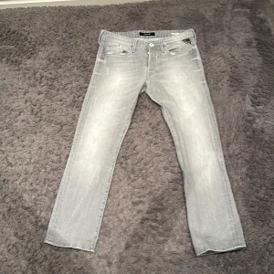 Grå jeans från Replay slim fit - Snygga grå jeans från Replay i en klassisk straight fit. De har en diskret tvättad look och är tillverkade i ett bekvämt denimtyg. Perfekta för en stilren vardagslook. Riktigt grisch och väldigt eftertraktade, som helt nya.                                 Storlek L32 W31