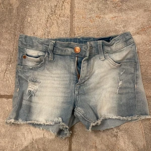 Ljusa jeansshorts med slitningar - Snygga ljusa jeansshorts med slitningar och fransiga kanter. De har en klassisk femficksdesign och en knappgylf. Perfekta för en avslappnad sommarlook. (Lite små för mig som har storlek s så kulle nog säga att de är xs)