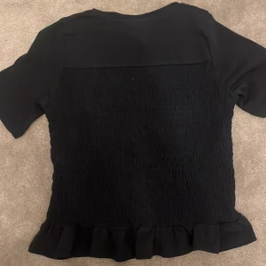 Mörkblå  topp från Gina Tricot - Snygg mörkblå topp från Gina Tricot med korta ärmar och volangdetalj vid nederkanten. Perfekt för en stilren look. 🖤