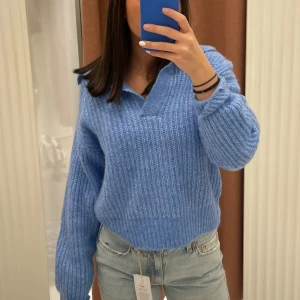 Blå stickad tröja - Hej! Säljer nu en mysig blå stickad tröja med långa ärmar och en avslappnad passform. Tröjan har en ribbad struktur och en liten krage. Använd endast fåtal gånger✨Perfekt nu när det är lite kyligare, men passar även till mildare sommarkvällar💕