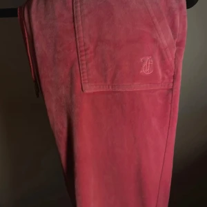 Rosa mjukisbyxor med broderad detalj - Snygga rosa mjukisbyxor med en broderad detalj på fickan. Perfekta för en avslappnad stil och bekväma att bära hela dagen. Byxorna har en enkel design med en mjuk känsla.