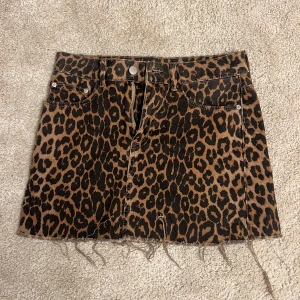 Leopardmönstrad kortkjol från Zara - Snygg leopardmönstrad kortkjol från Zara TRF Collection. Kjolen har en rå kant nertill och klassisk femficksdesign med knapp och dragkedja framtill. Köpt på Sellpy i mycket bra skick och är fortfarande det då den är använd en gång.