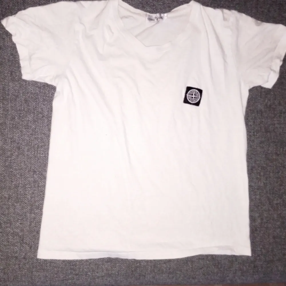 Vit Stone Island t-shirt i stl L, ser dock ut som stl M. Inga fläckar eller skavanker, 8/10 i skick! Vet dock ej om den är äkta så priser går att diskutera. Hör av dig för frågor eller liknande ☺️. T-shirts.