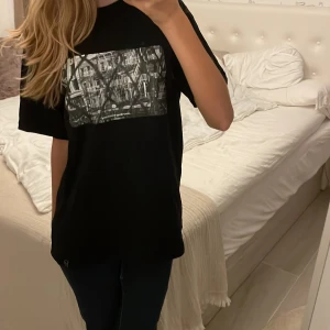 Svart t-shirt med tryck - Säljer en svart t-shirt från Pull&bear med ett coolt tryck av en byggnad på framsidan. Den är oversized och skön. 💕