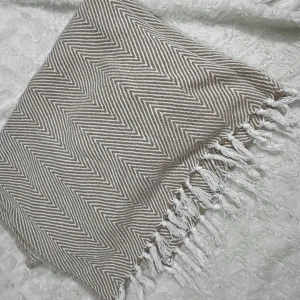 Beige och vit filt från Rusta Home - Säljer en superfin filt från Rusta Home i beige och vitt med ett snyggt sicksackmönster. Den är perfekt för att mysa till det i soffan eller som en extra värmande detalj i sängen. Filten har fransar på kanterna som ger en bohemisk touch. Perfekt för höst och vinter! 🍂❄️tyvärr är det som rivor, går nog bort med noppermaskin. 