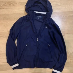 Ralph Lauren Vindjacka. OBS priset går att ändra! - Tja! Säljer nu denna riktigt snygga Ralph lauren vindjackan i färgen marinblå. Jackan är i bra skick och är i storlek 14 - 16. Skriv jättegärna om du har någon fråga eller något annat. 🙌