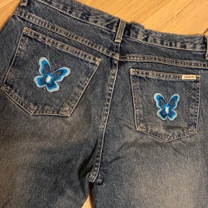 Midwaist bootcutjeans med fjärilsdetaljer - Jätte söta och snygga retro jeans. Är lite nötta längst ner men annars i väldigt bra skick!