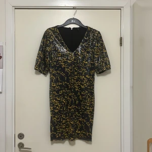 Festklänning i svart och gul i paljetter  - 88 cm lång, ny oanvänd, festklänning, dragkedja bak i ryggen 